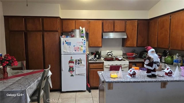 kitchen with a kitchen bar, white appliances, light tile patterned floors, and vaulted ceiling