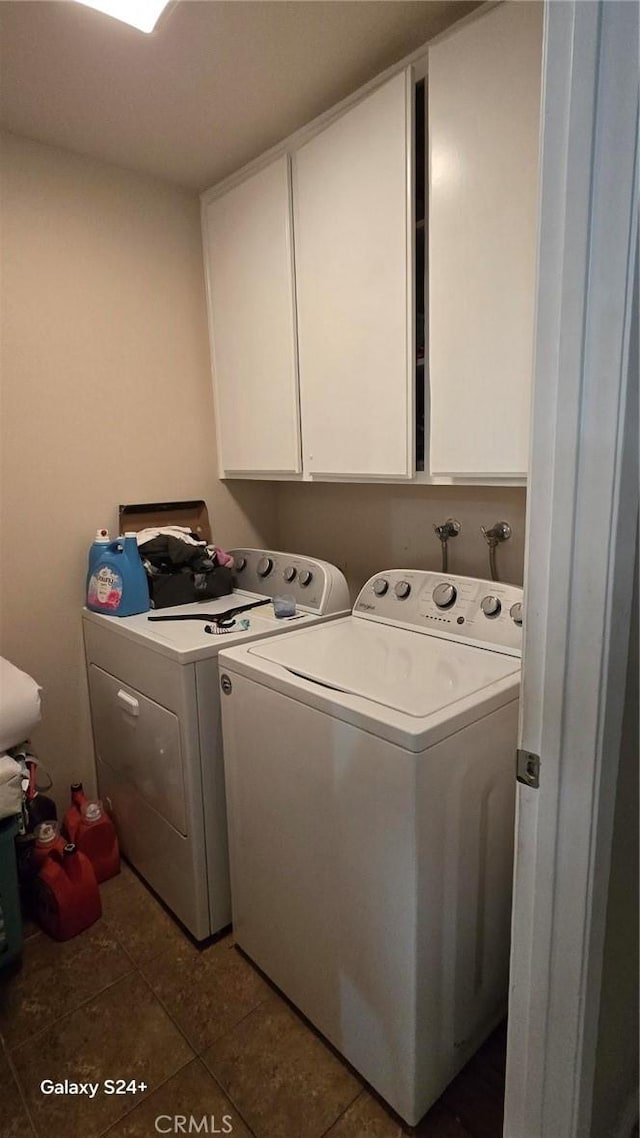 laundry area with separate washer and dryer, dark tile patterned floors, and cabinets