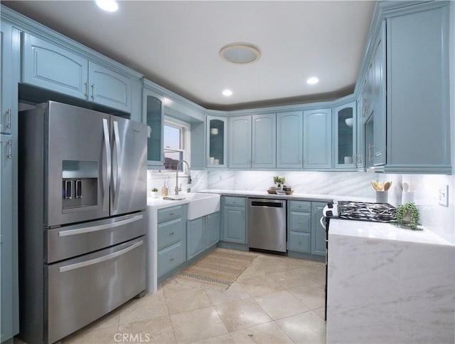 kitchen featuring appliances with stainless steel finishes, glass insert cabinets, a sink, and decorative backsplash