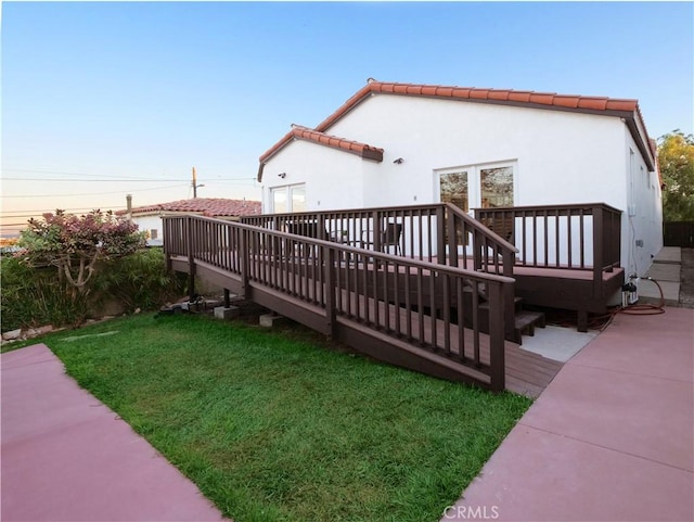 exterior space with a lawn, a wooden deck, and stucco siding