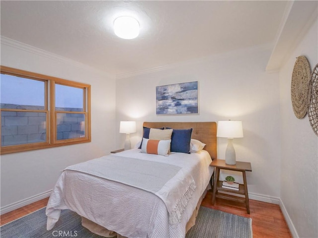 bedroom with ornamental molding, wood finished floors, and baseboards