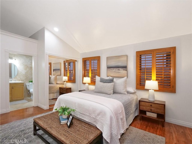 bedroom with recessed lighting, wood finished floors, baseboards, vaulted ceiling, and ensuite bath