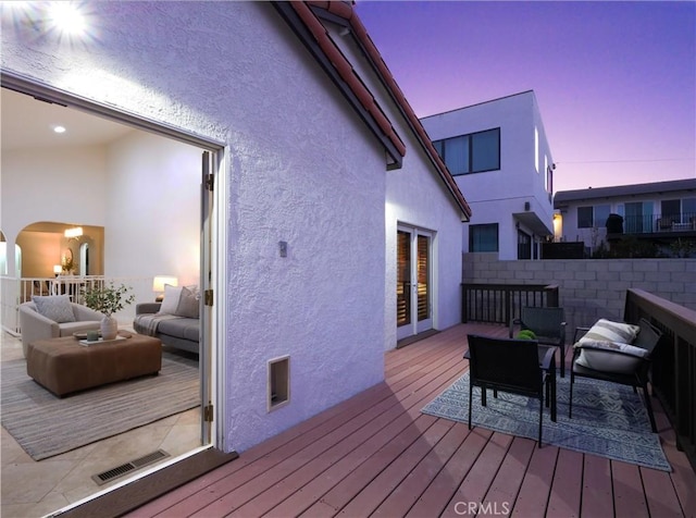 deck at dusk with visible vents and an outdoor living space