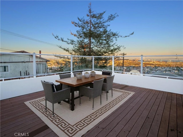 deck at dusk featuring outdoor dining area