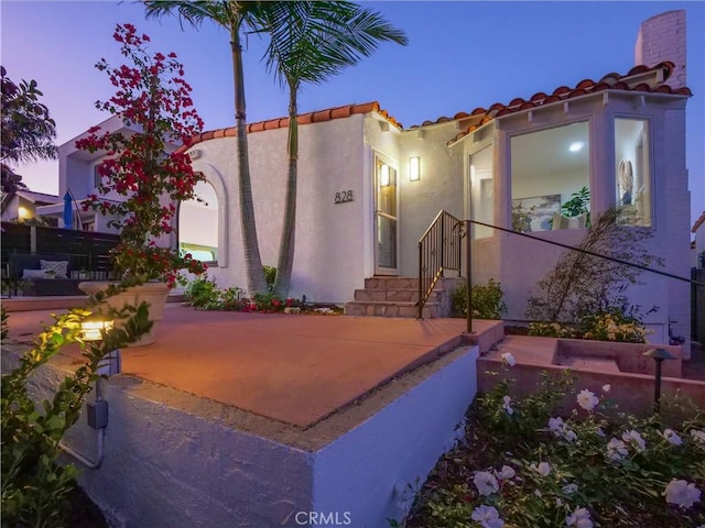 exterior space with a tile roof and stucco siding