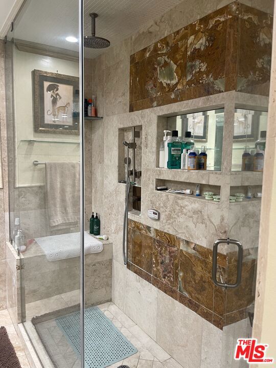 bathroom with a shower with shower door and crown molding