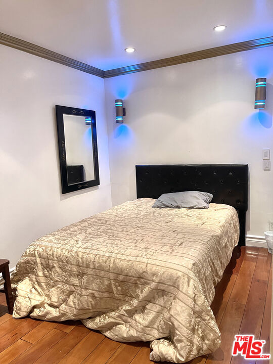 bedroom with crown molding and hardwood / wood-style flooring