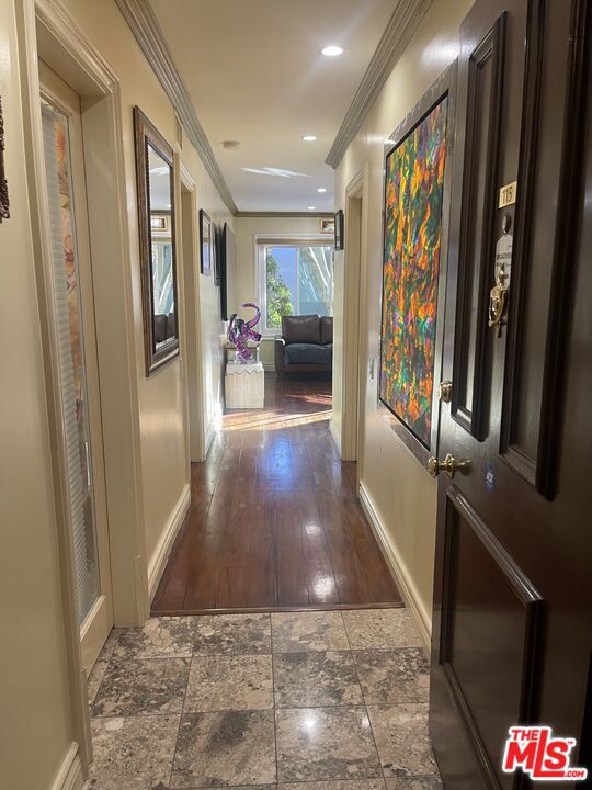 hallway with dark hardwood / wood-style floors and ornamental molding