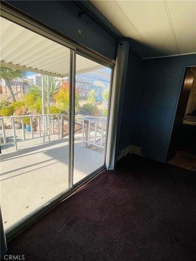 doorway with dark colored carpet and plenty of natural light