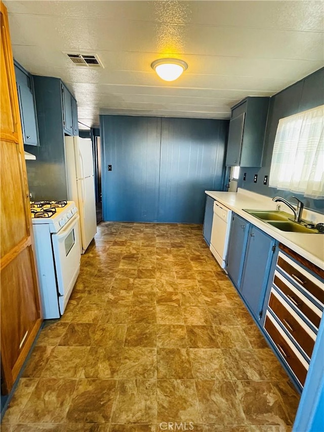 kitchen featuring blue cabinetry, white appliances, wooden walls, and sink