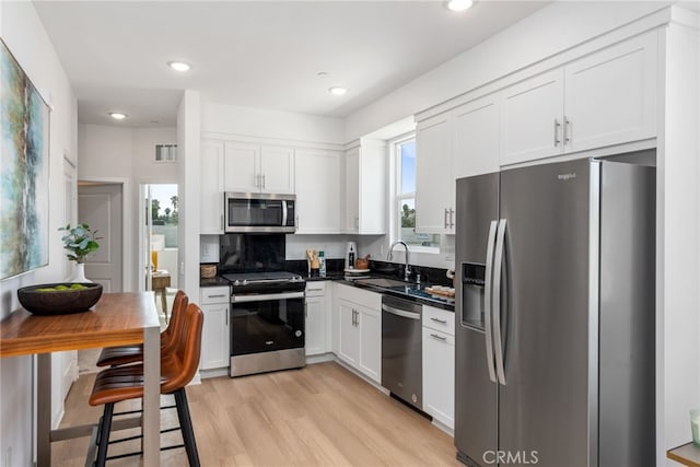 kitchen featuring white cabinets, stainless steel appliances, light hardwood / wood-style floors, and sink