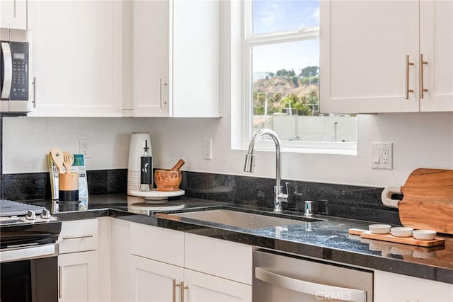 kitchen featuring white cabinets, dark stone countertops, sink, and stainless steel appliances