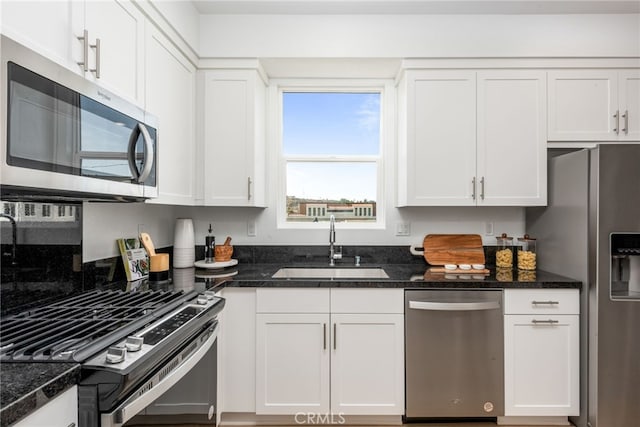 kitchen featuring white cabinets, sink, appliances with stainless steel finishes, and dark stone counters