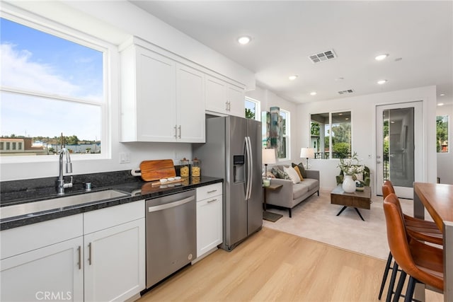 kitchen with sink, white cabinets, light hardwood / wood-style flooring, and appliances with stainless steel finishes