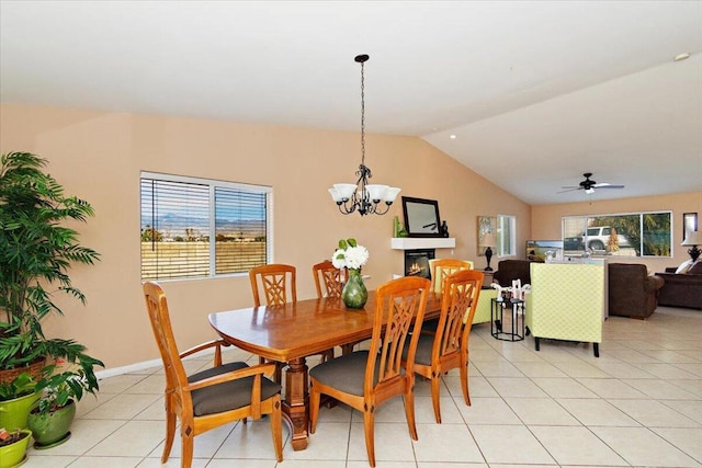 dining room with ceiling fan with notable chandelier, light tile patterned flooring, and vaulted ceiling