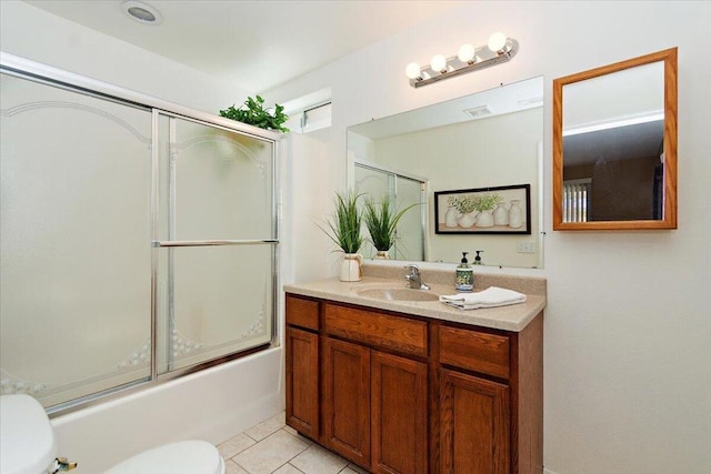 full bathroom with tile patterned floors, vanity, bath / shower combo with glass door, and toilet