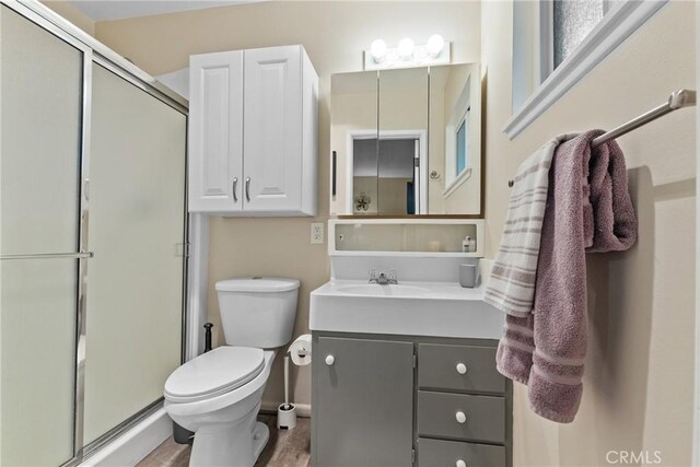 bathroom with hardwood / wood-style floors, vanity, a shower with shower door, and toilet