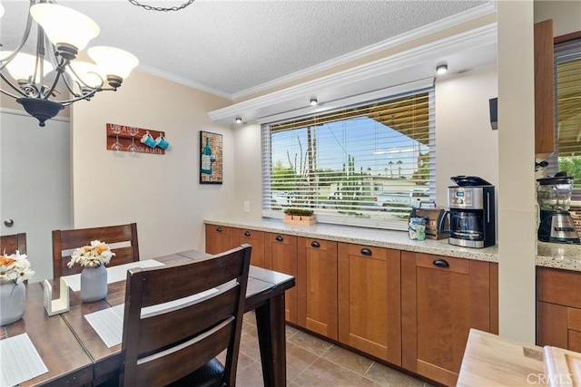 kitchen featuring crown molding, light stone countertops, a textured ceiling, light tile patterned flooring, and a chandelier
