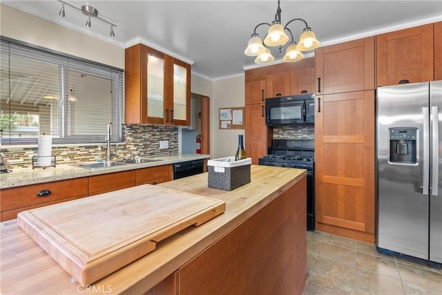 kitchen featuring sink, a notable chandelier, backsplash, decorative light fixtures, and black appliances