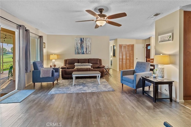 living room featuring wood-type flooring, a textured ceiling, and ceiling fan