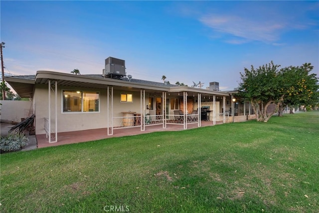back of property with a patio, central AC, and a lawn