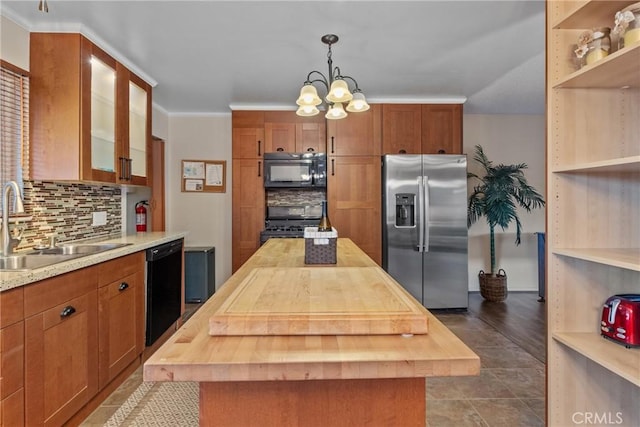 kitchen with black appliances, wood counters, a kitchen island, and hanging light fixtures