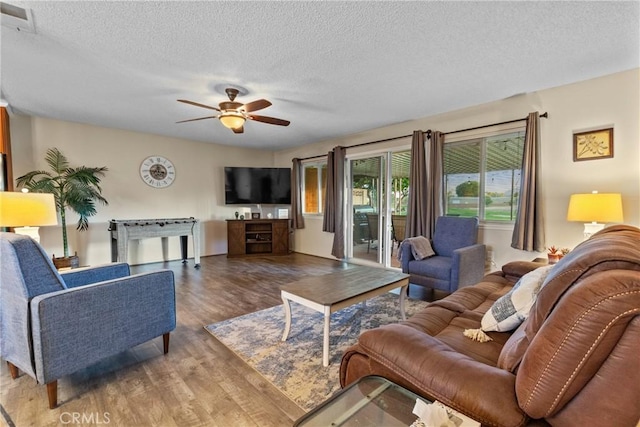 living room with ceiling fan, light hardwood / wood-style flooring, and a textured ceiling