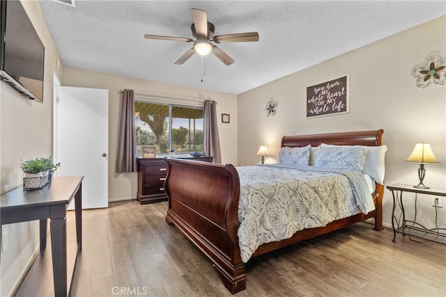 bedroom featuring ceiling fan, wood-type flooring, and a textured ceiling