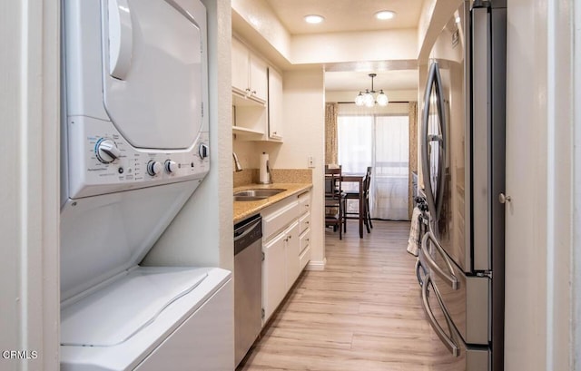 kitchen featuring white cabinetry, stainless steel appliances, hanging light fixtures, and light hardwood / wood-style flooring