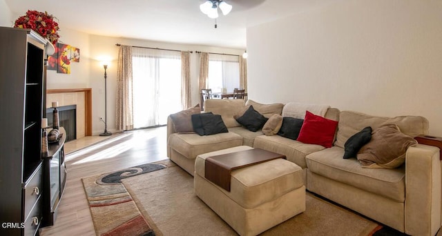 living room featuring a fireplace, ceiling fan, and light hardwood / wood-style flooring