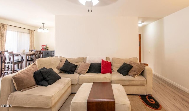 living room featuring ceiling fan with notable chandelier and light hardwood / wood-style floors