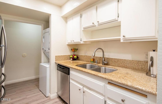 kitchen featuring light stone countertops, dishwasher, sink, stacked washing maching and dryer, and light hardwood / wood-style flooring