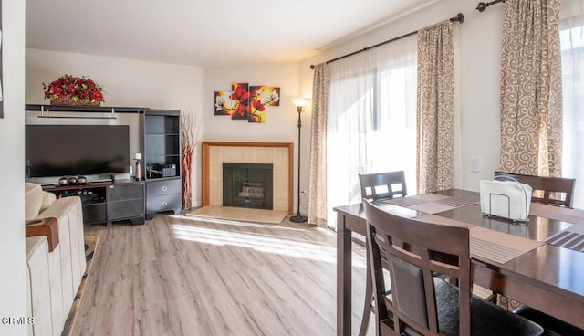 dining area featuring a fireplace, light wood-type flooring, and plenty of natural light