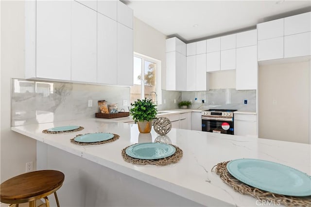 kitchen with white cabinets, appliances with stainless steel finishes, tasteful backsplash, and a breakfast bar area