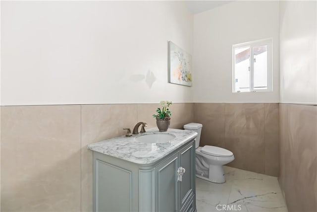 bathroom with vanity, toilet, and tile walls