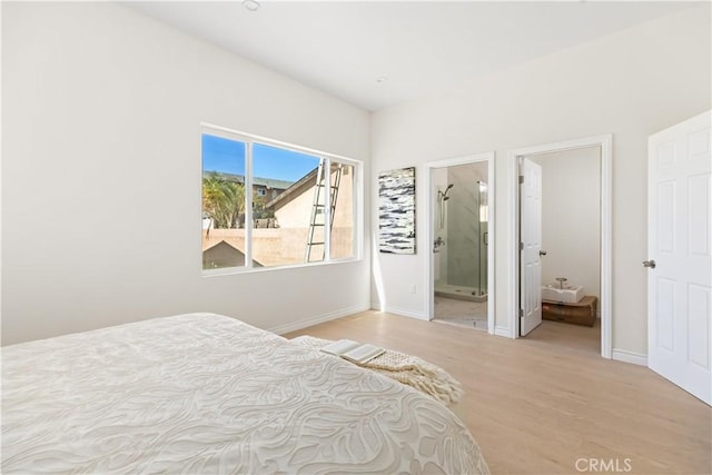 bedroom with connected bathroom and light hardwood / wood-style flooring