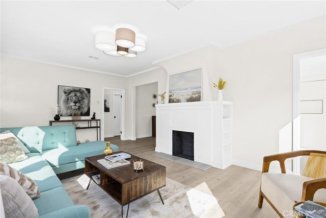 living room with light wood-type flooring and ornamental molding