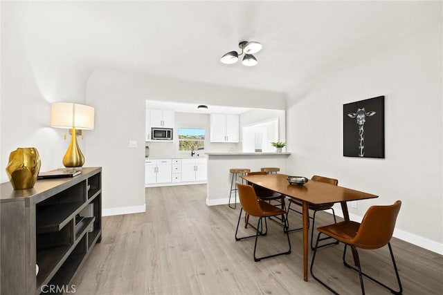 dining space with sink and light wood-type flooring