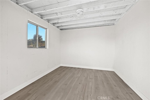 empty room with beam ceiling and hardwood / wood-style flooring