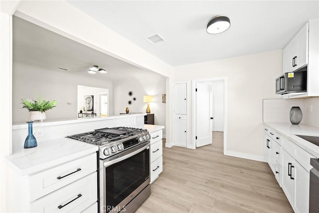 kitchen with white cabinets, light stone countertops, light wood-type flooring, and stainless steel appliances