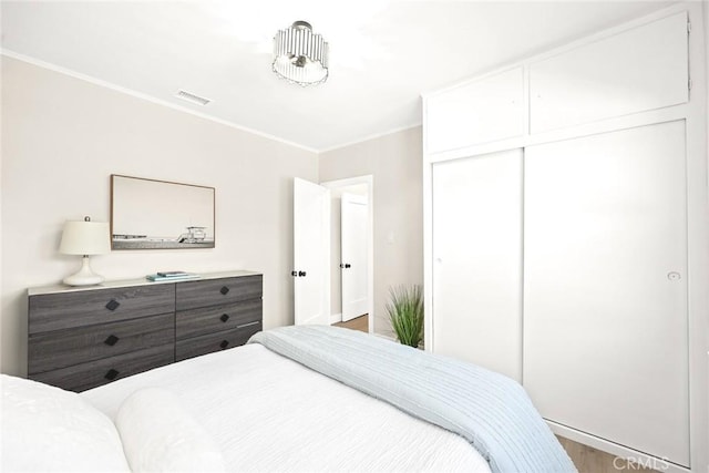 bedroom featuring hardwood / wood-style floors, crown molding, and a closet