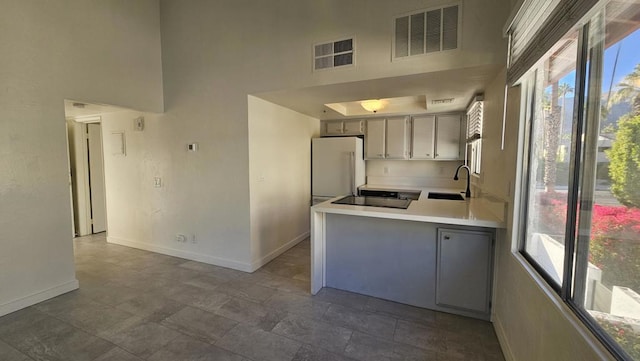 kitchen featuring gray cabinetry, plenty of natural light, white fridge, and kitchen peninsula