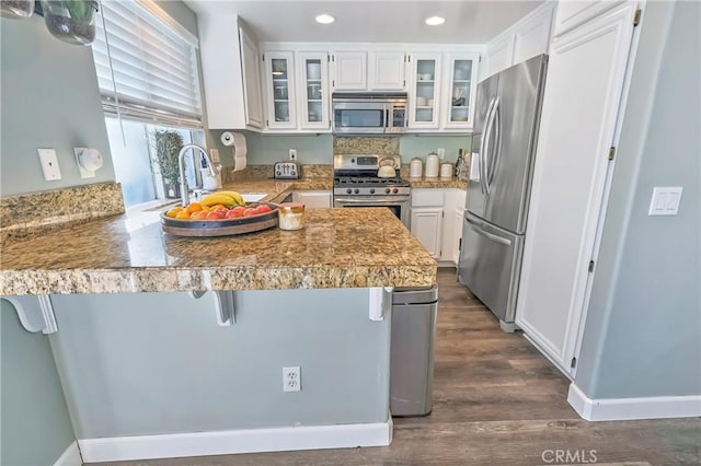 kitchen with white cabinetry, sink, a breakfast bar area, kitchen peninsula, and stainless steel appliances