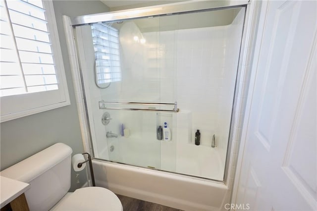 full bathroom featuring enclosed tub / shower combo, hardwood / wood-style floors, vanity, and toilet