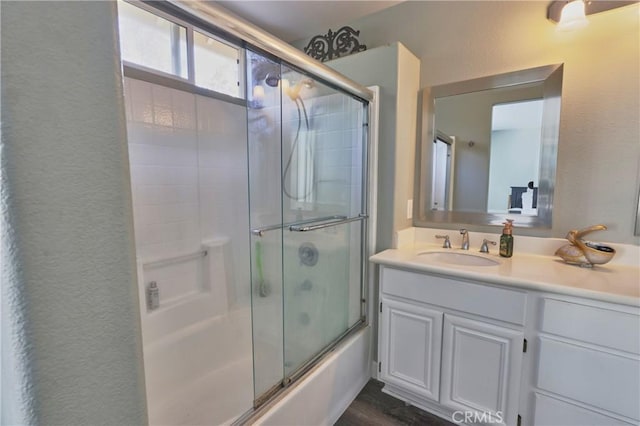 bathroom featuring bath / shower combo with glass door, wood-type flooring, and vanity