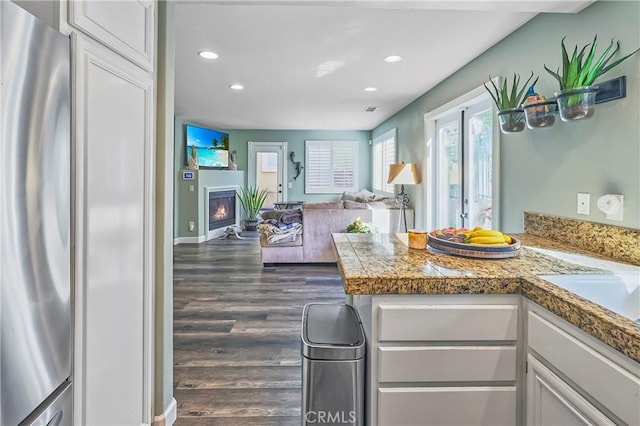 kitchen with stainless steel refrigerator, dark hardwood / wood-style flooring, kitchen peninsula, and white cabinets