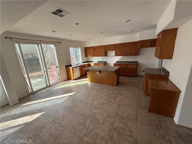 kitchen featuring tile patterned flooring, a kitchen island, stainless steel dishwasher, and sink