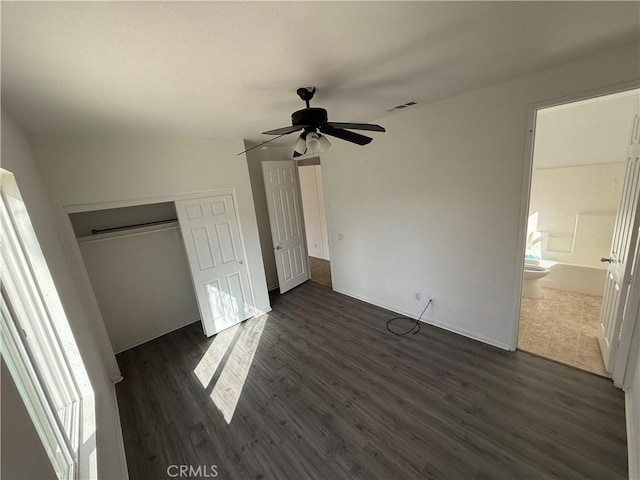 unfurnished bedroom featuring ceiling fan, a closet, dark wood-type flooring, and vaulted ceiling