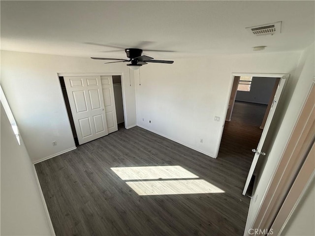 unfurnished bedroom featuring ceiling fan, a closet, and dark wood-type flooring