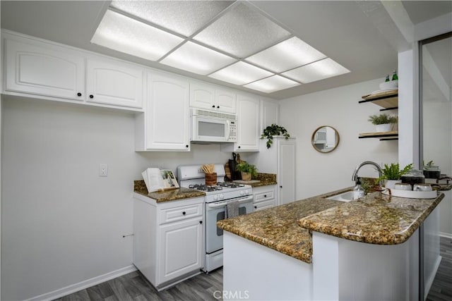 kitchen featuring sink, white appliances, white cabinetry, dark wood-type flooring, and dark stone counters